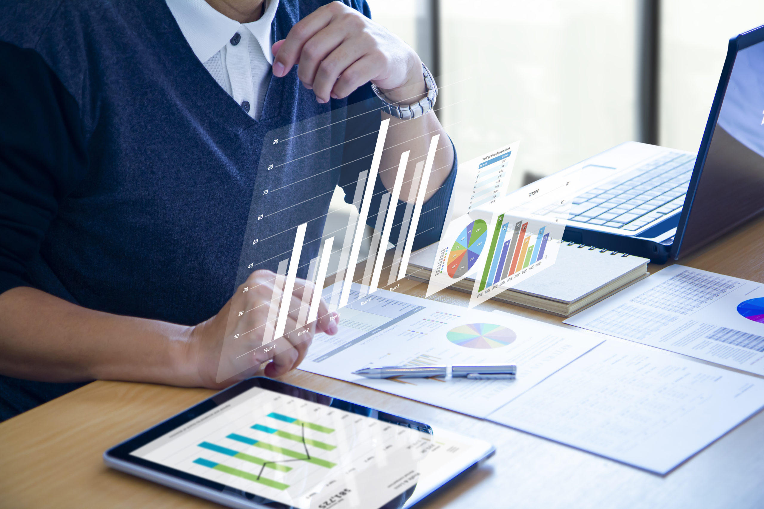 Businessman with virtual reality graphics is deeply reviewing financial reports for a return on investment, ROI, or investment risk analysis.