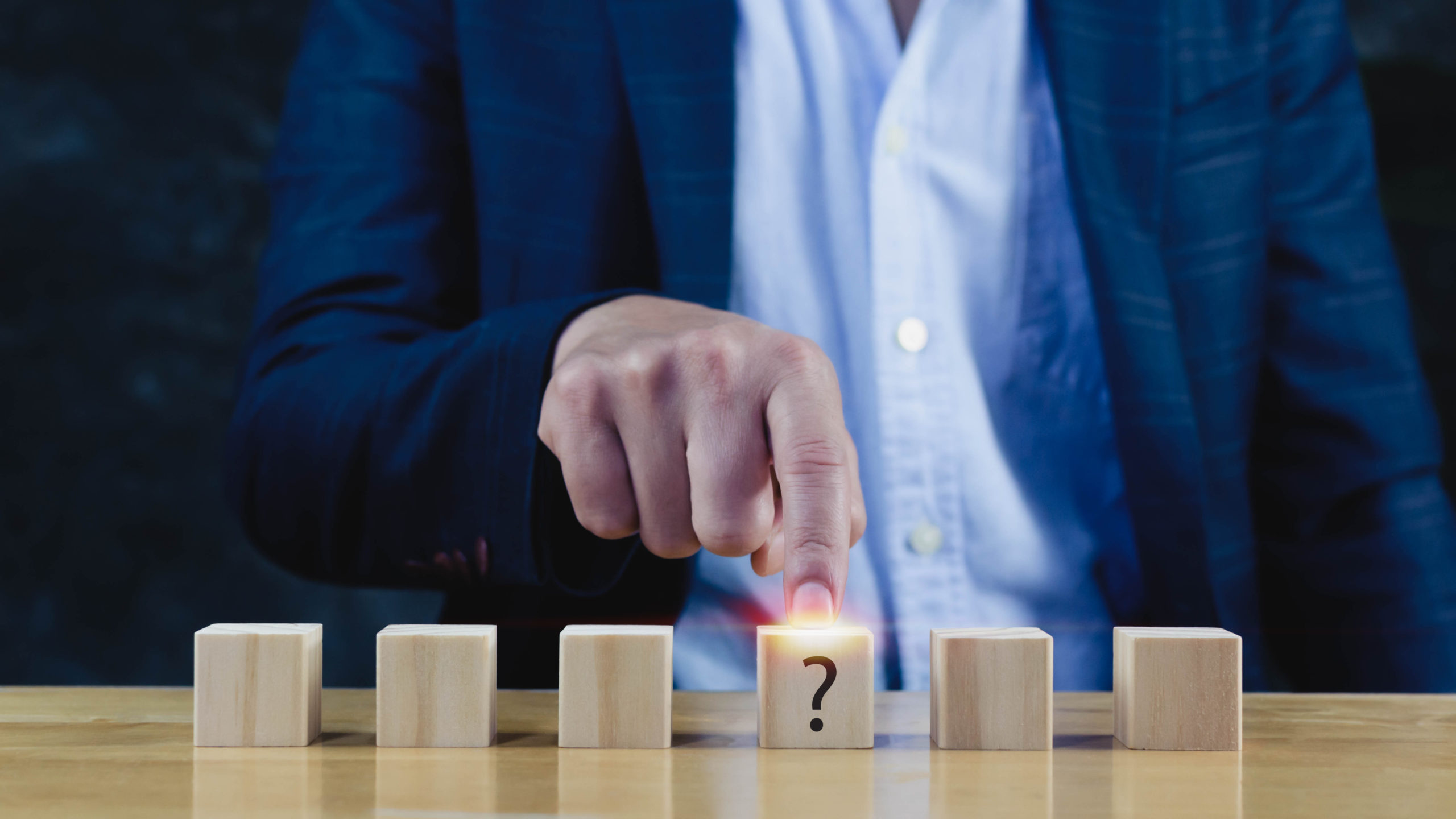 Businessman hand choose the wooden block with Questions Mark (  ) on wooden cube block on table ,FAQ( frequency asked questions), Answer, Q and A, Information, Communication and interrogation Concepts